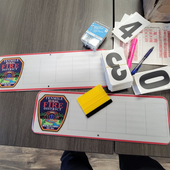 Fire district signs, number cards, pens, ink pad, eraser, and a marker list on a table.