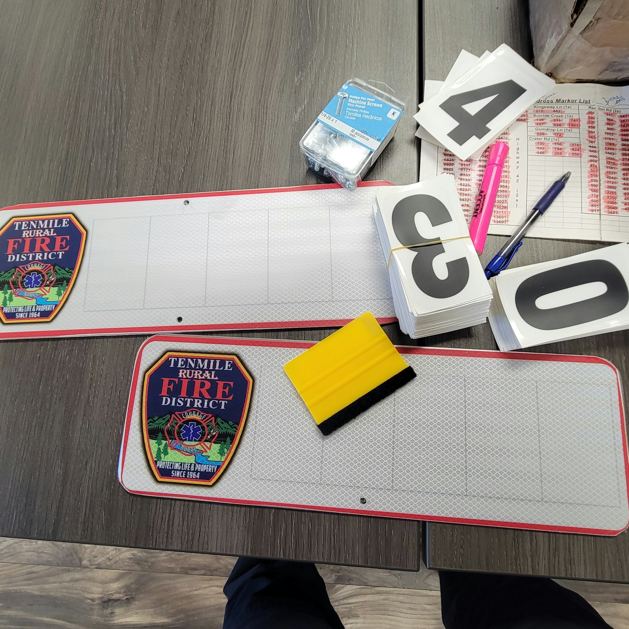 Fire district signs, number cards, pens, ink pad, eraser, and a marker list on a table.