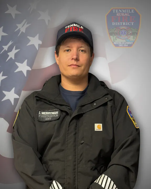 A firefighter with badges in front of a US flag backdrop.