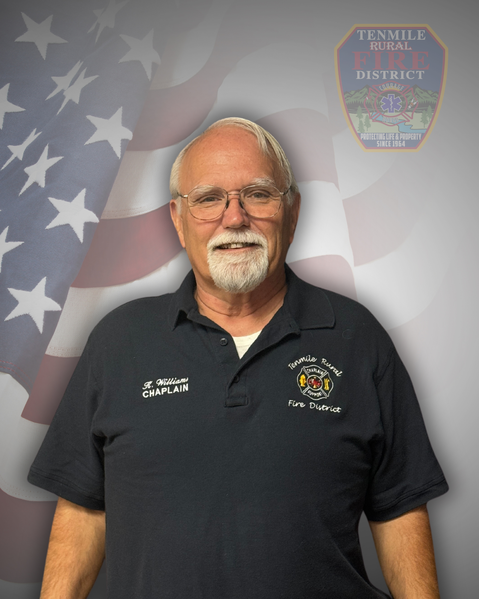 A smiling man with a mustache, wearing a "Chaplain" shirt, with a U.S. flag and fire district emblem backdrop.