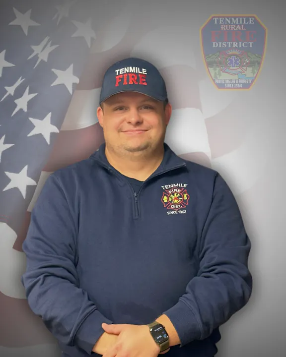 Man in a Tenmile Fire Dept. uniform with an American flag background.