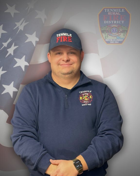 Man in a Tenmile Fire Dept. uniform with an American flag background.