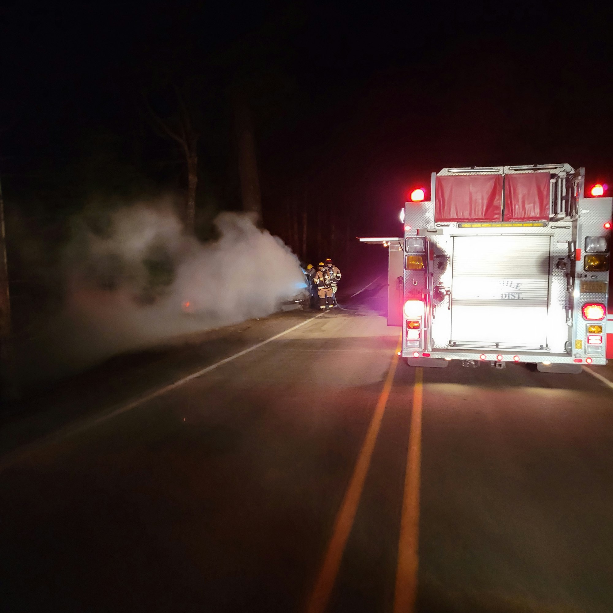 A fire truck and firefighter with smoke, possibly at an emergency scene. The image is rotated; the truck should be upright.