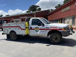 A fire department utility truck parked outside a red building on a sunny day.