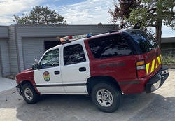 A red and white emergency vehicle with roof lights parked in front of a building.
