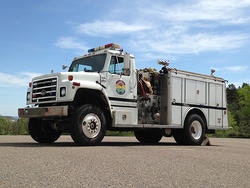 A white fire truck parked outdoors on a sunny day.