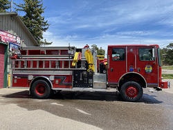 A red fire truck parked outside a building under a clear blue sky.