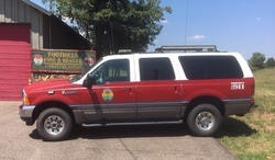 A red and white emergency vehicle parked in front of a building with a sign.