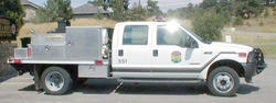 A white utility truck, possibly a service vehicle, parked on a road with a utility box on the back.