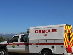 A rescue vehicle parked outdoors with mountains in the background under a clear blue sky.