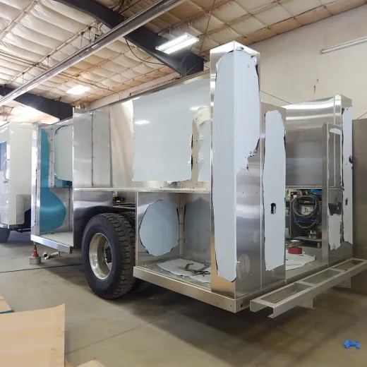 A vehicle being constructed or modified in a workshop, showing metal frames and large tires.