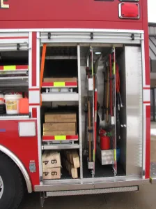 Fire truck storage compartment with tools, wooden blocks, and equipment.
