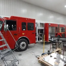 A partially assembled fire truck in a workshop, with tools and materials nearby.