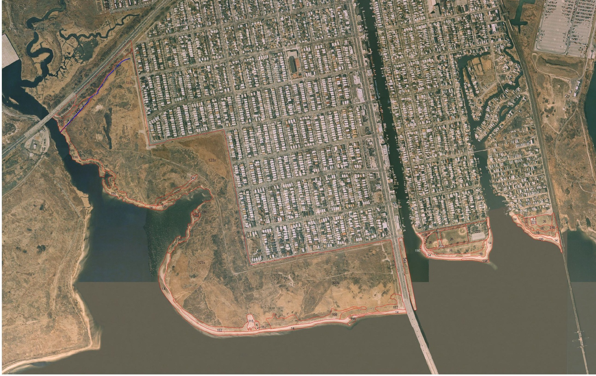 Aerial view of a coastal urban area with streets, buildings, and a bridge over water.