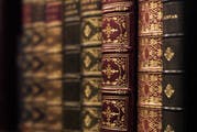 A row of ornate, leather-bound books with intricate gold designs on the spines.