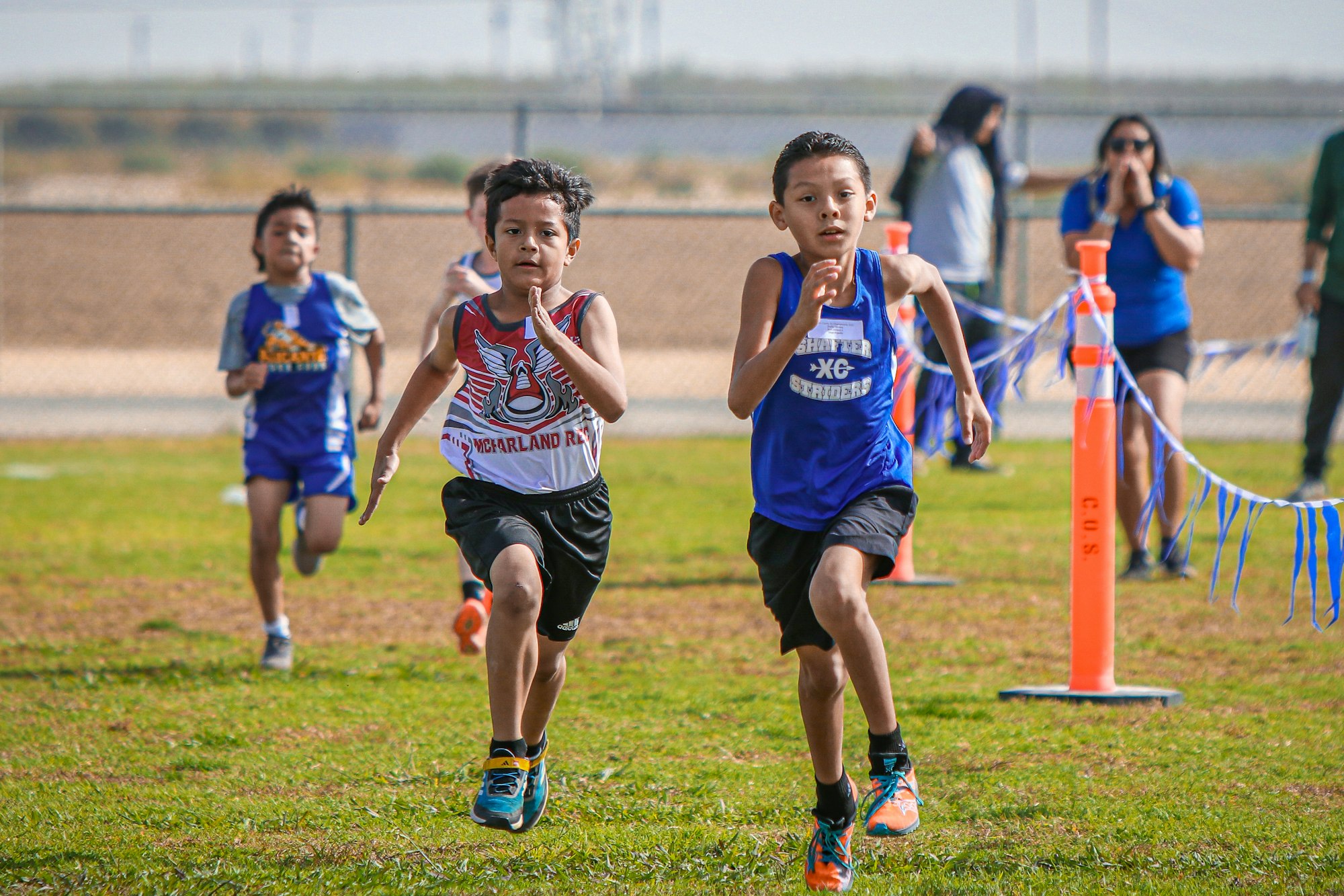 Kids running a race with spectators in the background.