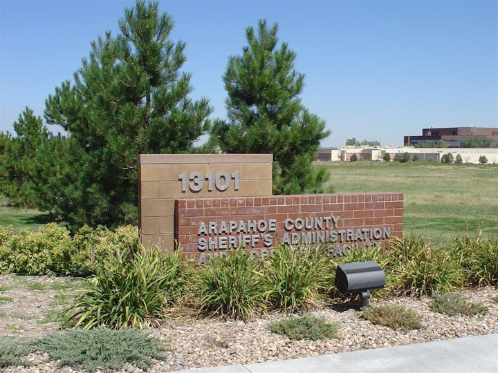 Sign for Arapahoe County Sheriff's Administration near trees and grass, located at 13101.