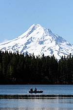 A serene scene featuring a snow-capped mountain towering over a lake, with two people in a boat enjoying the view.