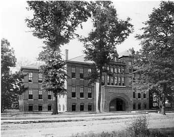 Historic building with arch entrance, surrounded by large trees, giving an old-time feel.