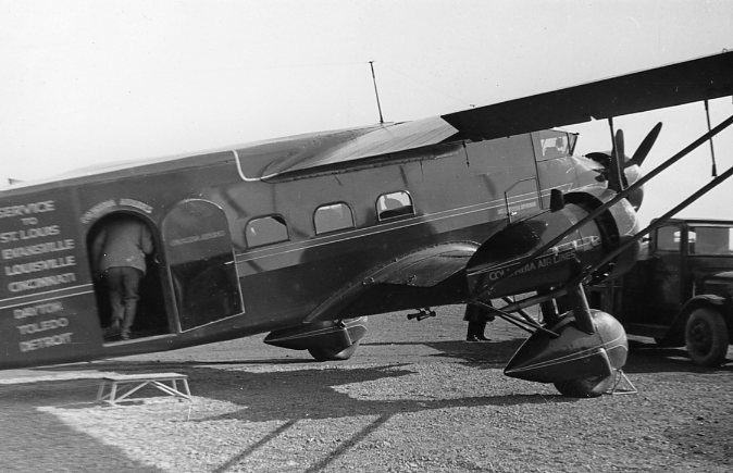 Vintage airplane, propeller, and "American Airlines" text; black and white photo.