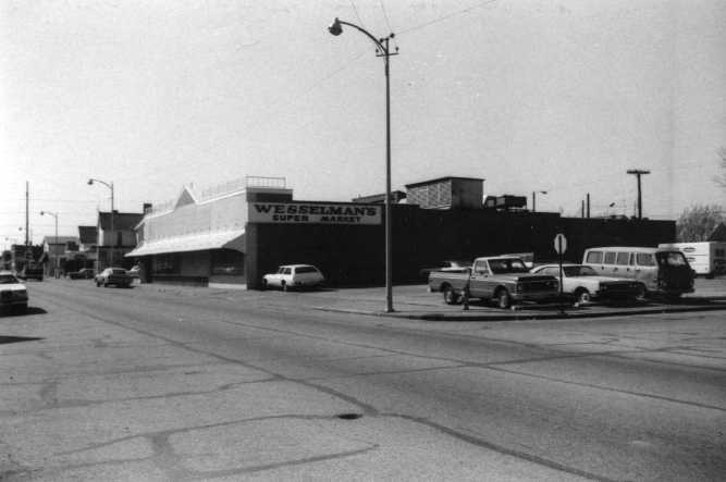 Black and white photo of a street with cars and a building labeled "Wesselman's."