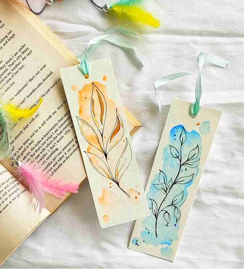 Handmade bookmarks with leaf designs, colorful splashes, ribbons, and feathers on a book page background.