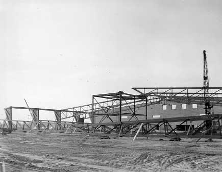 Construction site with steel framework of a building in progress, crane in the background, and no people visible.