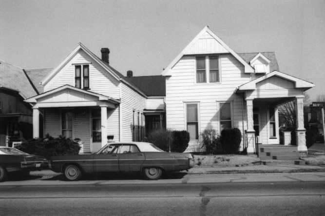 Two white houses and a vintage car on a street. Black and white photo.