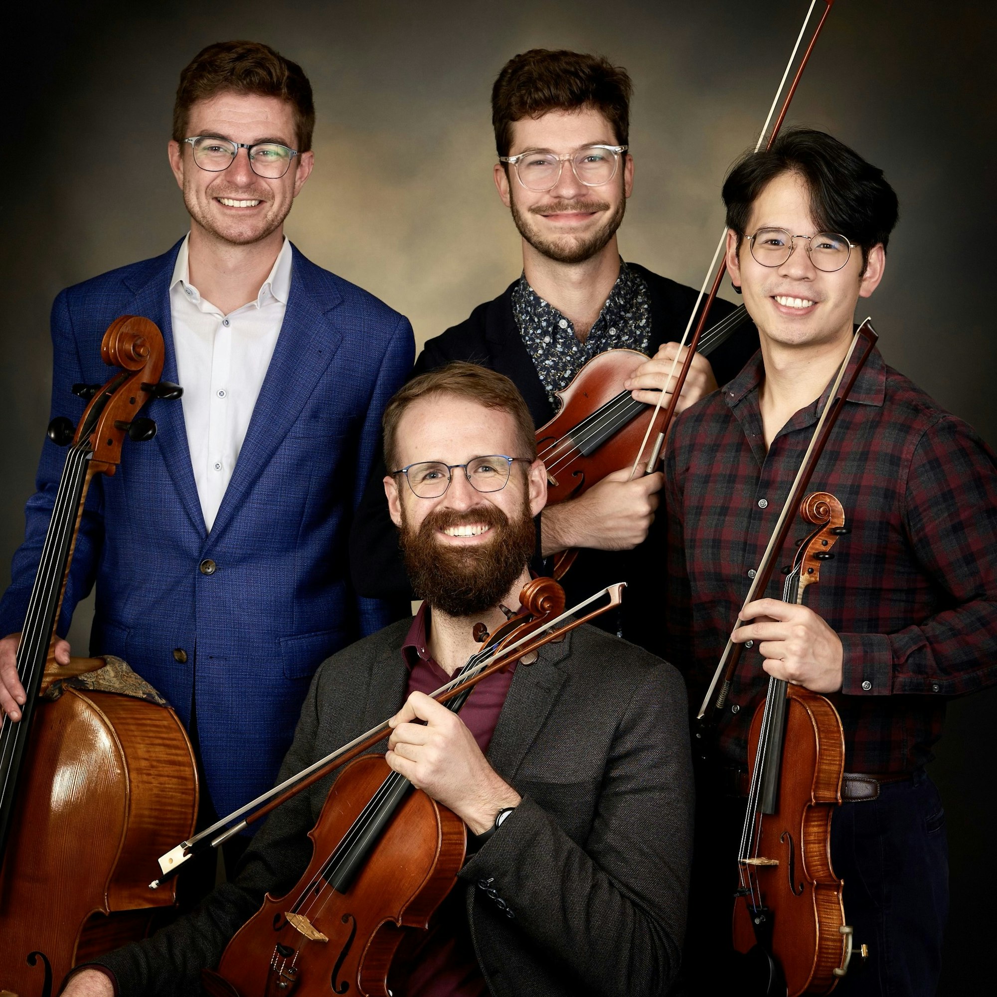 Four smiling musicians holding a cello and violins.