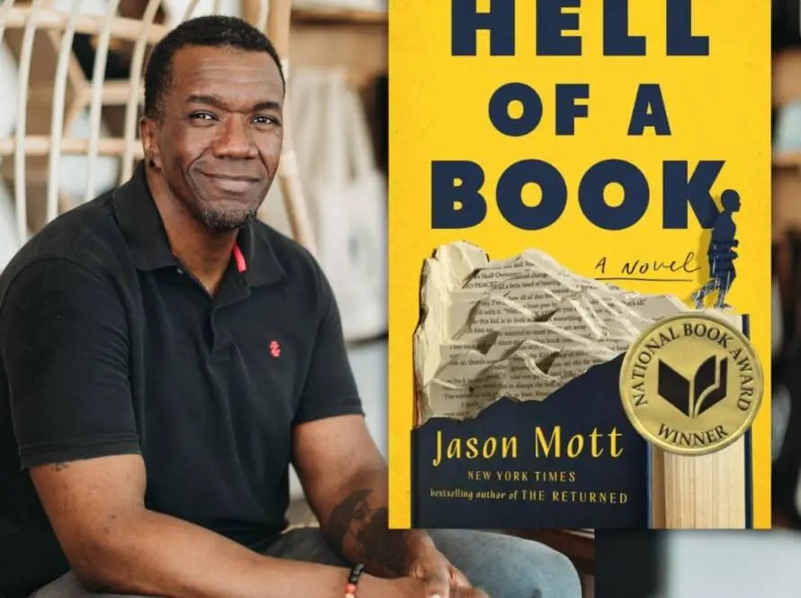 A man smiling beside his book "Hell of a Book," displaying a National Book Award badge.