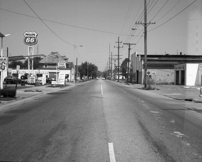 Deserted street with vintage gas station signs and old buildings.