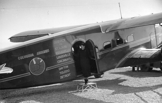 A vintage photo of a person stepping out of a Columbia Airlines plane, with various city names listed on it.