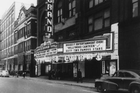 Vintage photo of the Grand theater marquee, promoting "Hollywood Canteen" with "62 famous stars," a classic car parked outside.