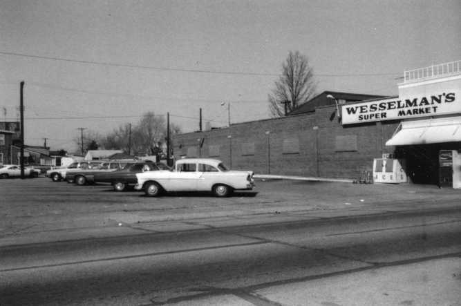 Vintage photo of cars parked outside Wesselman's Super Market, showcasing mid-20th-century architecture and vehicles.