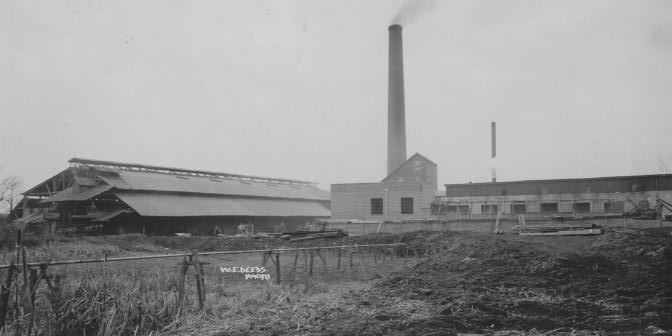 Black and white photo of an industrial site with buildings and smokestacks.