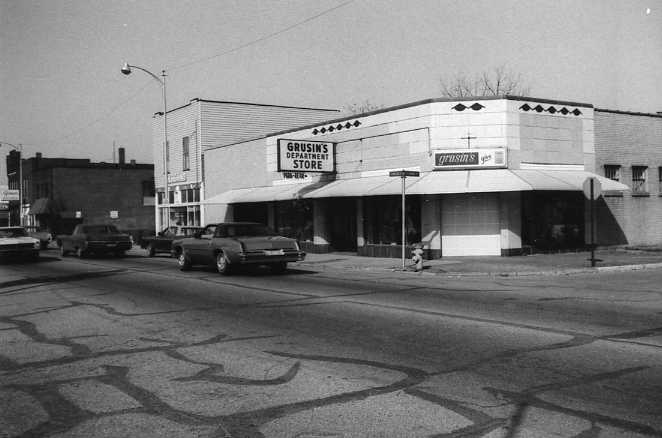 Black and white photo of a street with cars and a store named "Grusin's Department Store."