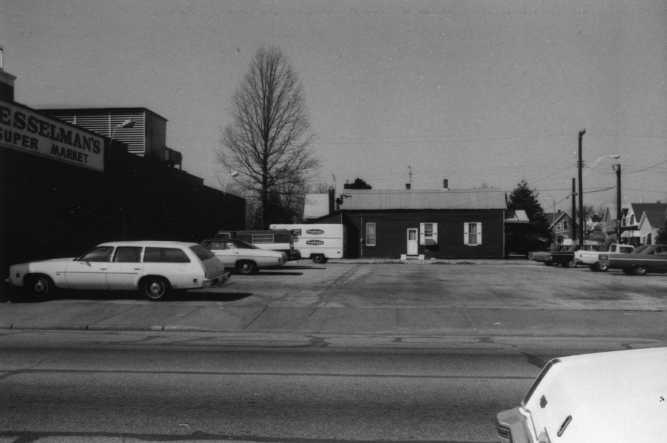 Black and white photo of a street with vintage cars and a building with a "Super Market" sign.