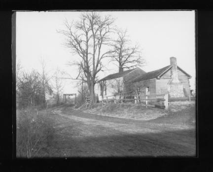 Old rural house with bare trees and a fence.