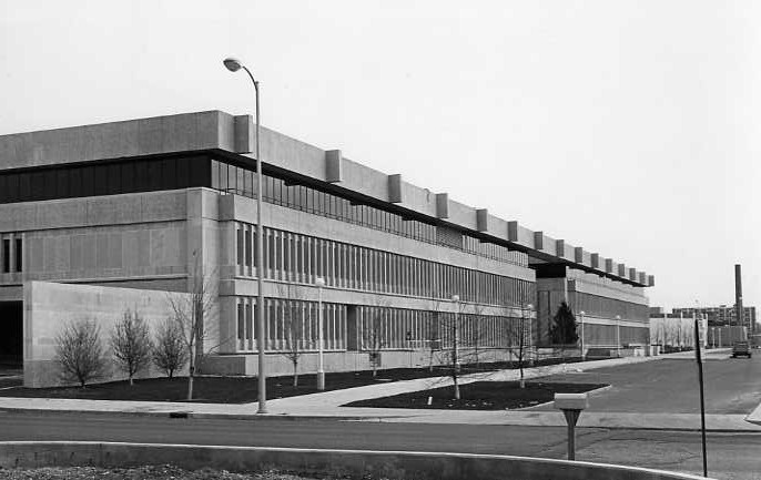 A black and white photo of a modern building with rows of windows, no people visible.