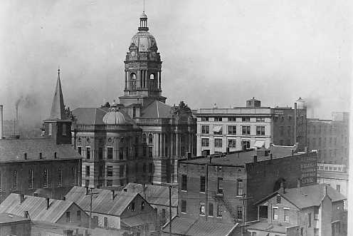 Historic black and white photo of an old cityscape with a prominent domed building and various other structures.