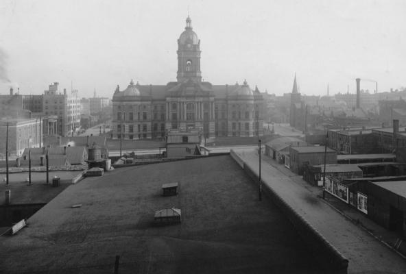 Historical photo of a cityscape with prominent building, flat roofs, and urban development. Black and white, old-time aesthetic.