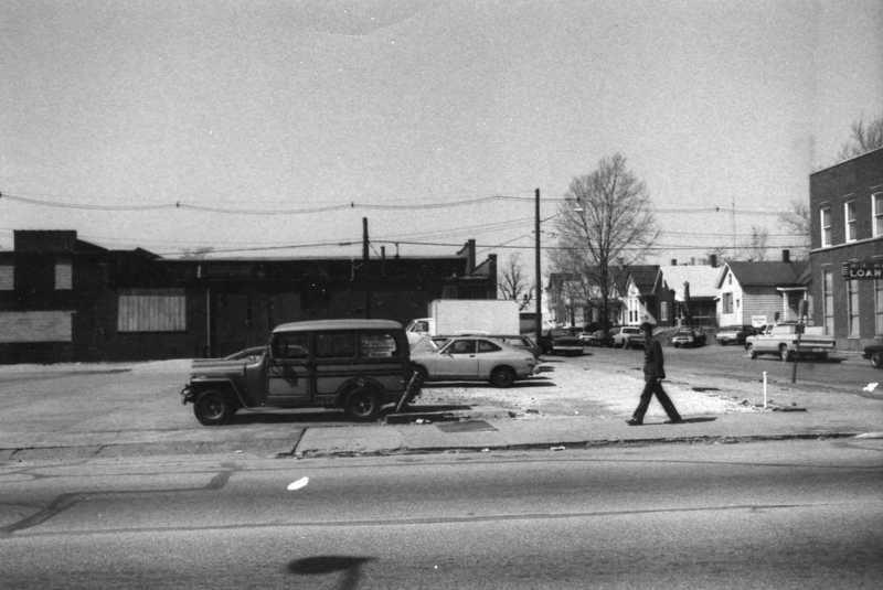 Urban street scene with pedestrian, cars, and buildings.