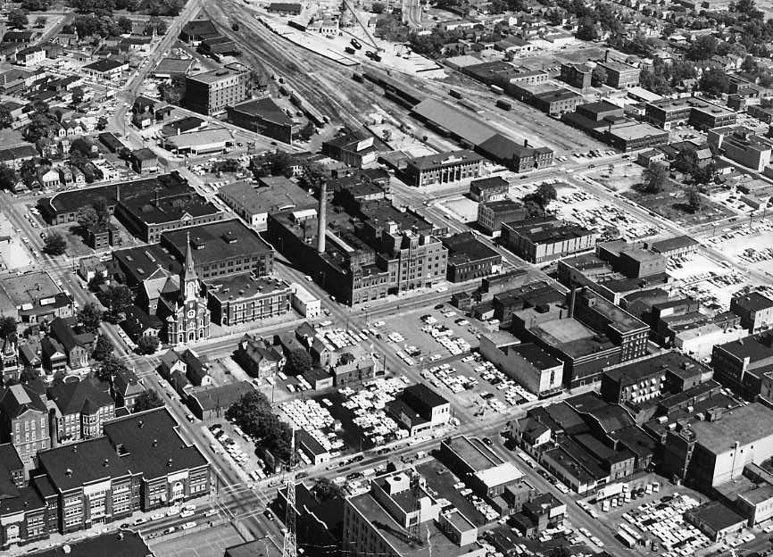 Aerial view of an urban area with buildings, roads, and vehicles.