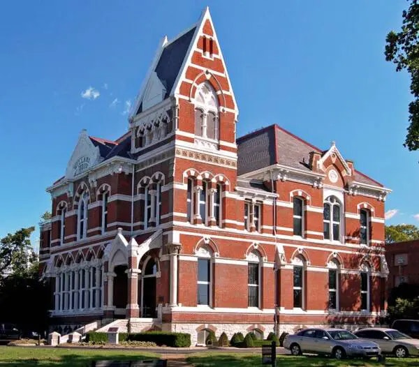 Victorian-style red brick building with white trim, large arched windows, and a pointed roof.