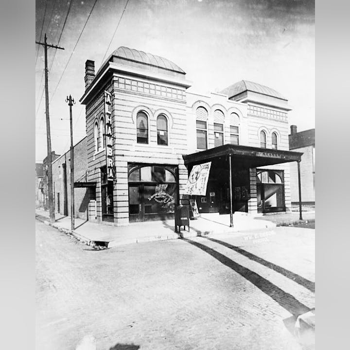 Vintage photo of the Alhambra building with arched windows and a sign, possibly a theater or public venue.