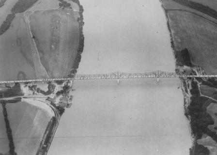 Aerial view of a bridge spanning over a river with surrounding farmland.