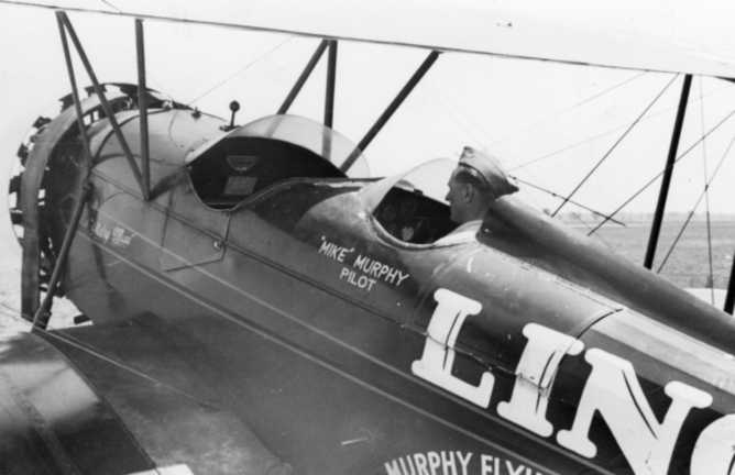 Vintage biplane with pilot inside, "LIN" text and "Mike Murphy Pilot" on side.
