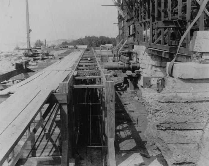 Construction site with wooden forms and reinforcing bars, likely for concrete structures.