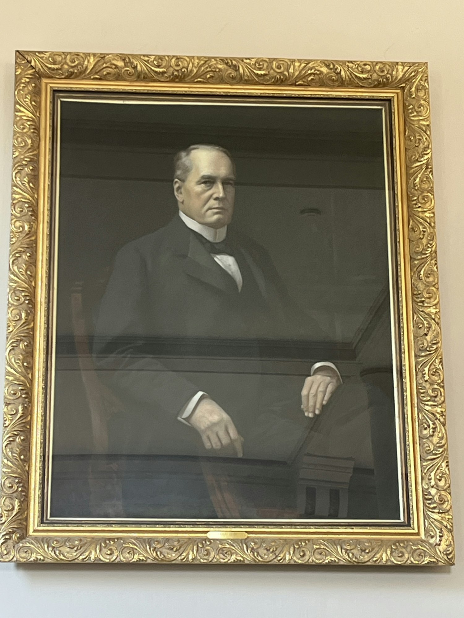 A portrait painting of a man in a gold ornate frame.