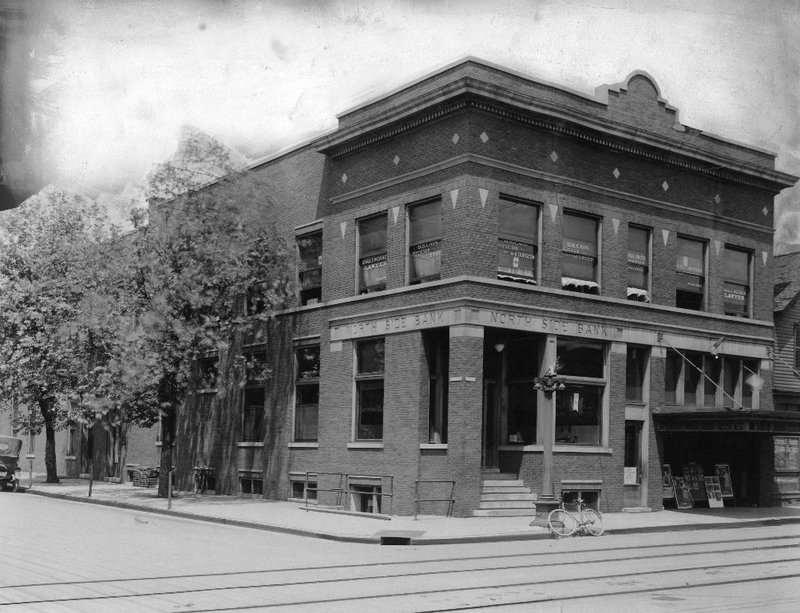 Vintage photo of a brick bank building with a bicycle parked outside.